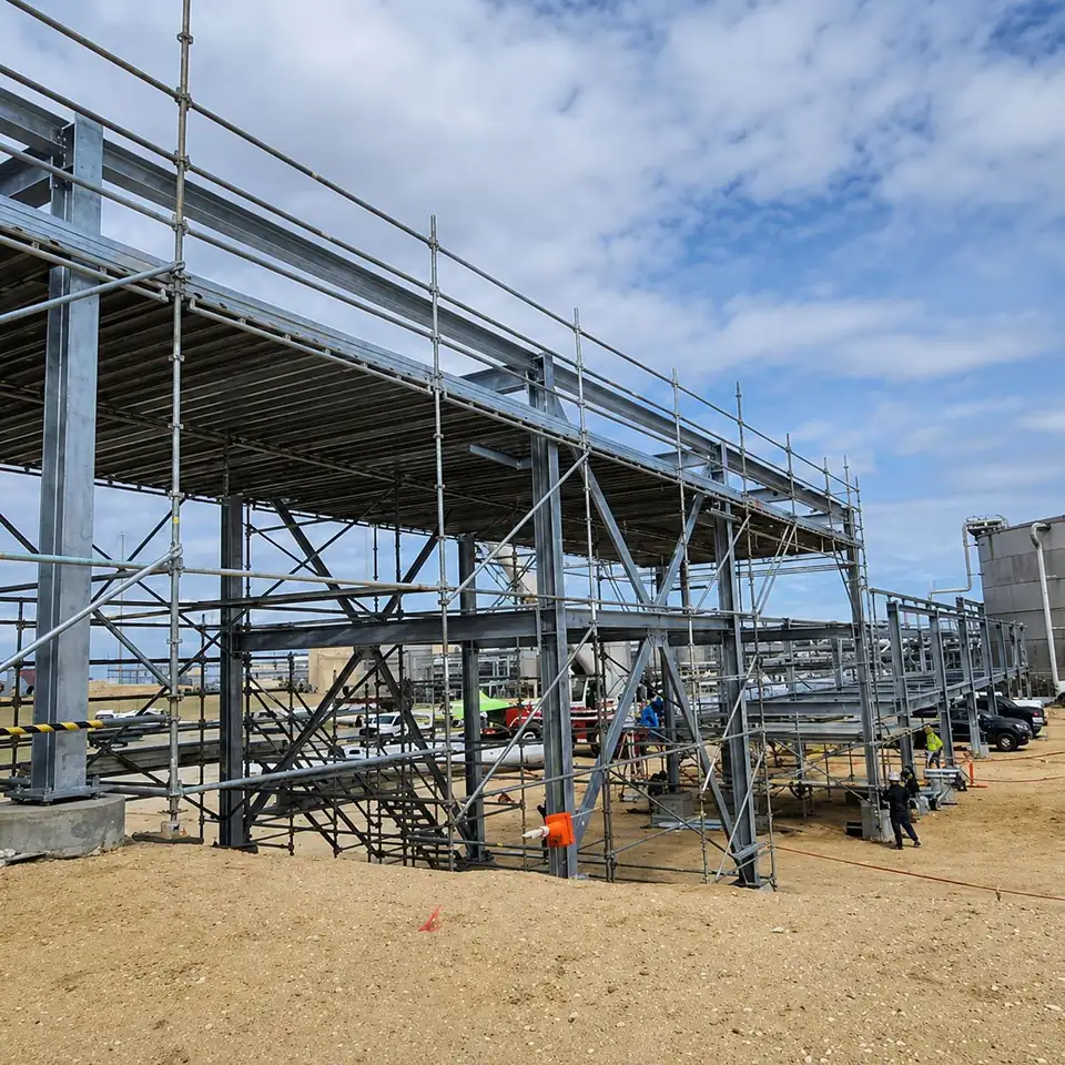 Long covered scaffold walkway with a stair tower on a construction site