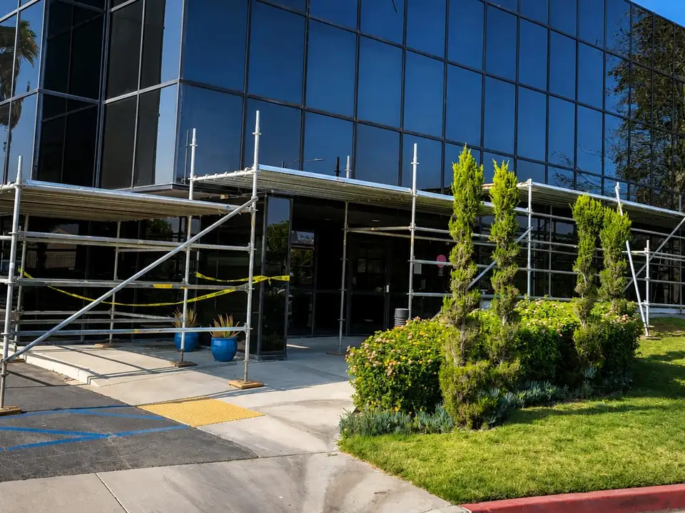 Scaffold pedestrian canopy over the entrance of a glass office building