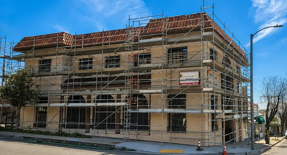 System scaffold wrapped around a two-story stucco building with a clay tile roof